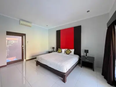 a bedroom with a bed and a red painting on the wall at The Lavana Bali Radiance Arjuna Villa Seminyak in Seminyak