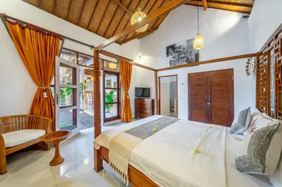 a bedroom with a bed and a chair in a room at villa mangga 2 chambres seminiak in Seminyak