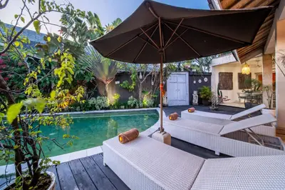a patio with two tables and an umbrella next to a swimming pool at Villa Armani Seminyak in Seminyak