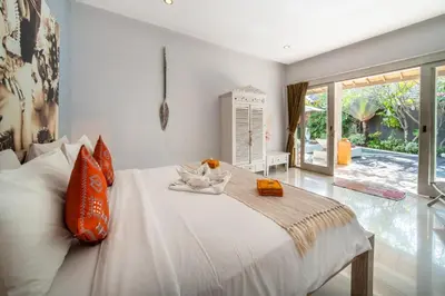 a bedroom with a large white bed with orange pillows at Villa Armani Seminyak in Seminyak