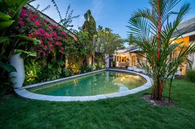 a swimming pool in the yard of a house with flowers at Villa Armani Seminyak in Seminyak