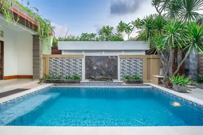 a swimming pool in the backyard of a house with palm trees at De Gani in Seminyak
