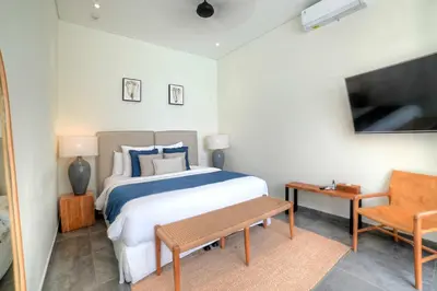 a bedroom with a bed and a table and a chair at Villa Sanya Berawa in Canggu
