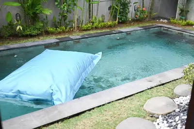 a swimming pool with a pillow in the grass at Villa Laksmi Legian in Seminyak
