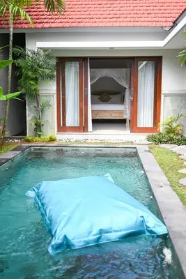 a large blue pillow in a swimming pool in front of a house at Villa Laksmi Legian in Seminyak