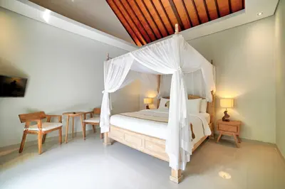 a bedroom with a canopy bed and a table and chairs at Villa Laksmi Legian in Seminyak