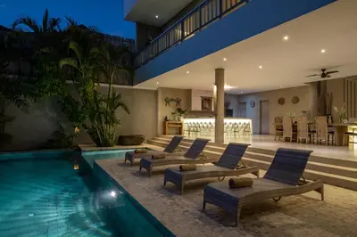a house with a swimming pool with chairs and a house at Spacious and Stylish Villa 3 Bedroom Seminyak in Denpasar
