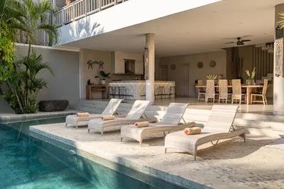 a group of lounge chairs next to a swimming pool at Spacious and Stylish Villa 3 Bedroom Seminyak in Denpasar