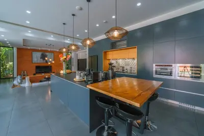 a kitchen with blue walls and a bar with stools at Villa Aless - Designer 4BR Villa with Sauna, Jacuzzi, Ice Bath, Gym & Rooftop in Canggu