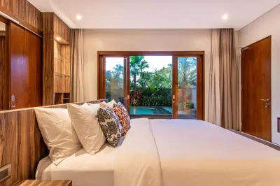 a bedroom with a large white bed with pillows at The Amarta Villa in Jimbaran