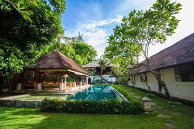 a backyard with a swimming pool and a house at Blind Dog Inn in Sanur