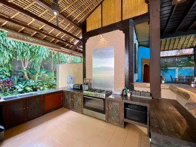 an outdoor kitchen with an aquarium in the background at Little Tree House in Sanur