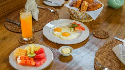 a table with two plates of eggs and fruit and toast at Villa Emmy by Elite Havens in Seminyak