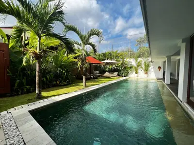 a swimming pool in front of a house at Tatkala Villa Seminyak in Seminyak