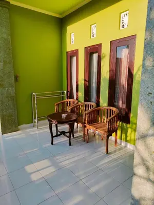 two benches and a table in a room with green walls at Berlian Inn Kuta Beach in Kuta