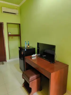 a room with a desk with a television and a stool at Berlian Inn Kuta Beach in Kuta