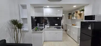 a kitchen with white cabinets and a black refrigerator at The Palmana Tropical Roofline Jayakarta Residence 50 in Legian