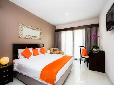 a bedroom with a large bed with an orange blanket at The Pavilion Hotel Kuta in Kuta