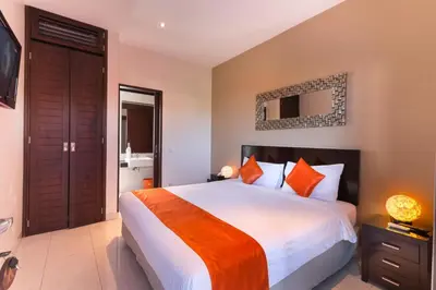 a bedroom with a large bed with orange pillows at The Pavilion Hotel Kuta in Kuta