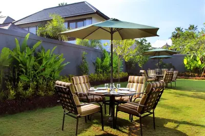 a table and chairs with an umbrella in a yard at Agata Villas Seminyak in Seminyak