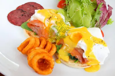 a plate of food with an egg sandwich and onion rings at Agata Villas Seminyak in Seminyak