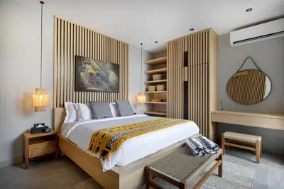 a bedroom with a large bed with a wooden headboard at Ananda Villa by Betterplace in Jimbaran