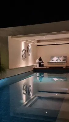 a swimming pool in a room with clocks on the wall at VILLA CELAVI 15 in Kerobokan