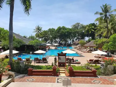 a pool at a resort with chairs and umbrellas at The Palmana Courtyard Jayakarta Residence 2 in Seminyak