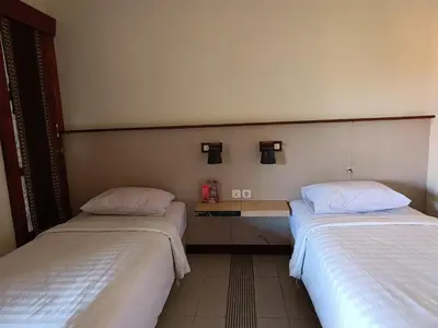 a room with two beds and a table between them at Keola Hotel Legian in Legian