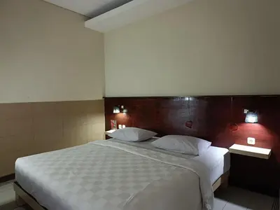 a bedroom with a large bed with a wooden headboard at Keola Hotel Legian in Legian