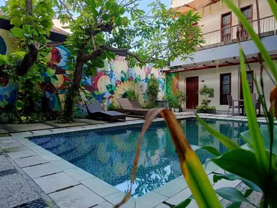 a pool in front of a building with a mural at Keola Hotel Legian in Legian