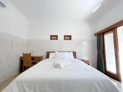 a bedroom with a large white bed with towels on it at Kubu19 Guest House in Seminyak