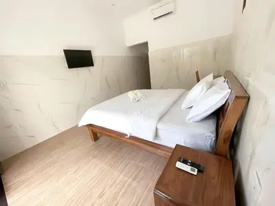 a small bedroom with a bed and a table at Kubu19 Guest House in Seminyak
