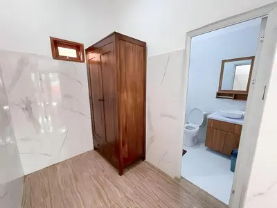 a bathroom with a toilet and a wooden door at Kubu19 Guest House in Seminyak