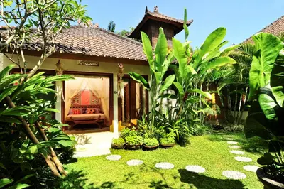 a garden in front of a house with a couch at Villa Domus De Janas in Seminyak