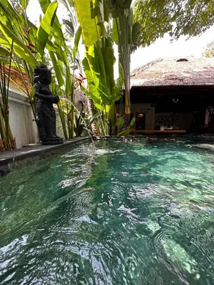 a pool of water with a statue next to a house at My Secret Home in Seminyak