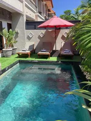 a swimming pool with a red umbrella and two chairs and an umbrella at Villa MARIE - KUTA - 6 Bedroom 4 Bathroom Villa - Great Location ! in Kuta