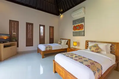 a bedroom with two beds and a flat screen tv at Kubal Villa and Living Seminyak in Canggu
