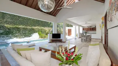 a living room with a couch and a tv at Ku Estate by Villa Finder in Seminyak