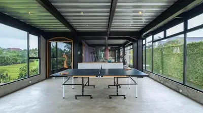a ping pong table in a room with large windows at Ku Estate by Villa Finder in Seminyak