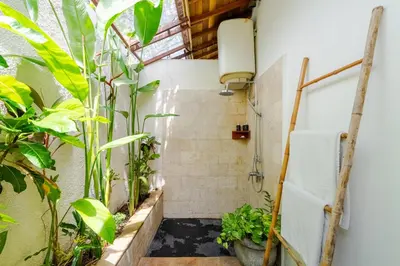 a bathroom with a shower with plants in it at Villa Belharra in Seminyak