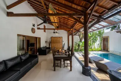 a living room with a table and a pool at Villa Belharra in Seminyak