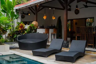 two chairs and a tub next to a swimming pool at Villa Belharra in Seminyak