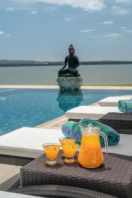 a table with two glasses of orange juice next to a pool at New Villa Selamanya in Ujung