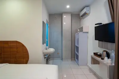 a bedroom with a bed and a bathroom with a shower at Cove De Tinaya in Legian
