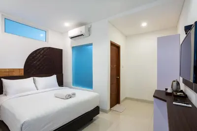 a bedroom with a white bed and a television at Cove De Tinaya in Legian