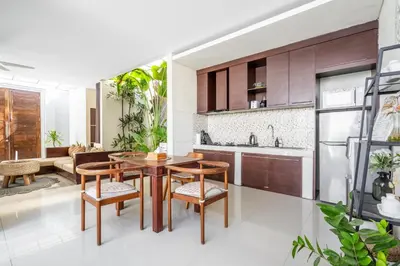 a kitchen and living room with a wooden table and chairs at The R Villa Toba - incl. Motorbikes in Seminyak