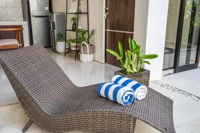 a wicker chair with two pillows on a porch at The R Villa Toba - incl. Motorbikes in Seminyak