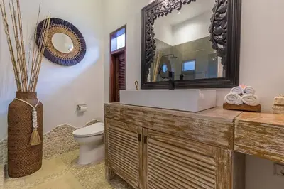 a bathroom with a sink and a toilet and a mirror at Villa Budha 1: 4bedrs 12m Pool, 700m2 garden with BBQ in Seminyak