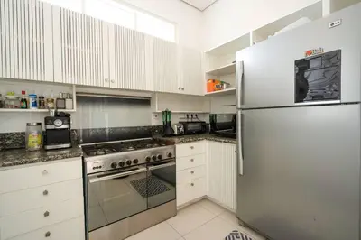 a kitchen with white cabinets and a stainless steel refrigerator at Villa Kainara 2 - Cozy villa in center of Seminyak in Seminyak